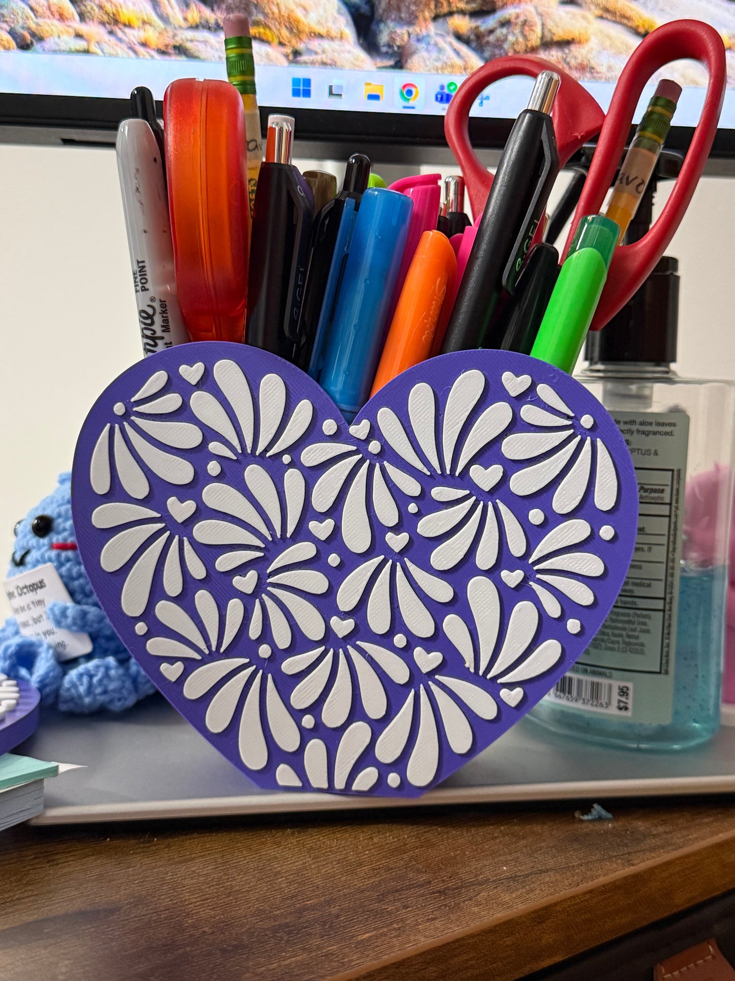 Purple heart-shaped pencil holder with stationery items on a desk